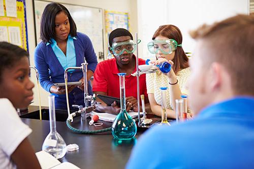 化学教室里，学生往坩埚里倒东西时，老师和学生都戴着护目镜