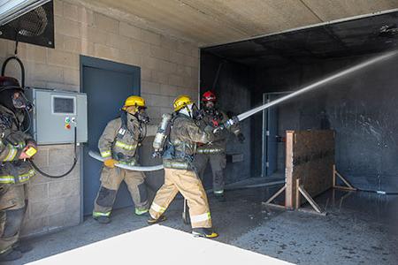 三名消防员在大楼内使用消防水带